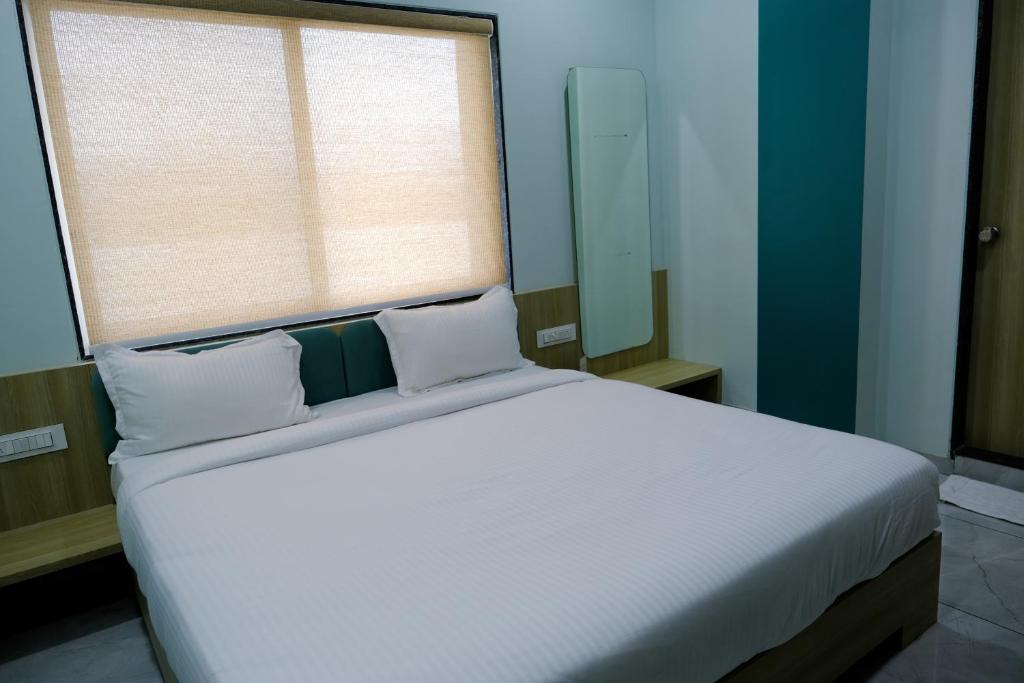 um quarto com uma grande cama branca e uma janela em Hotel Sai Unity Room em Garudeshwar