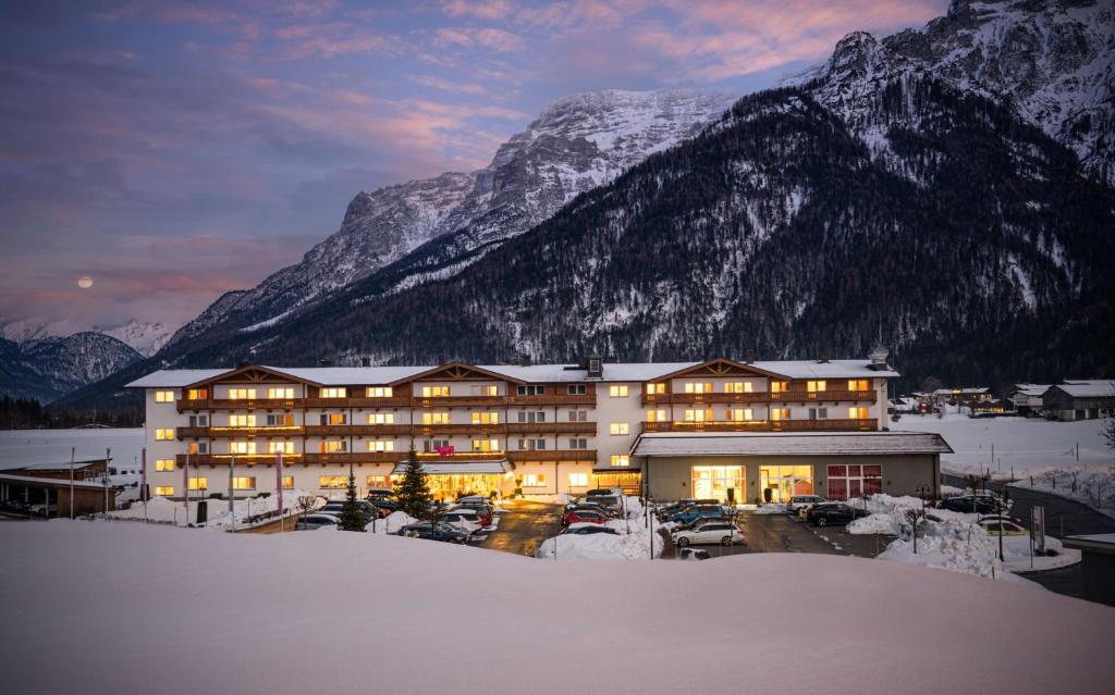 un gran edificio frente a una montaña nevada en elaya hotel steinplatte ehemals KUHOTEL by Rilano, en Waidring