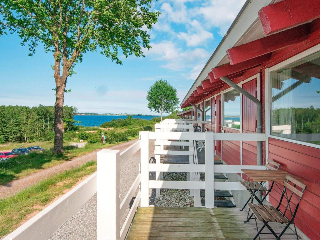 une véranda d'une maison rouge avec des bancs et un arbre dans l'établissement 6 person holiday home in Aabenraa, à Åbenrå