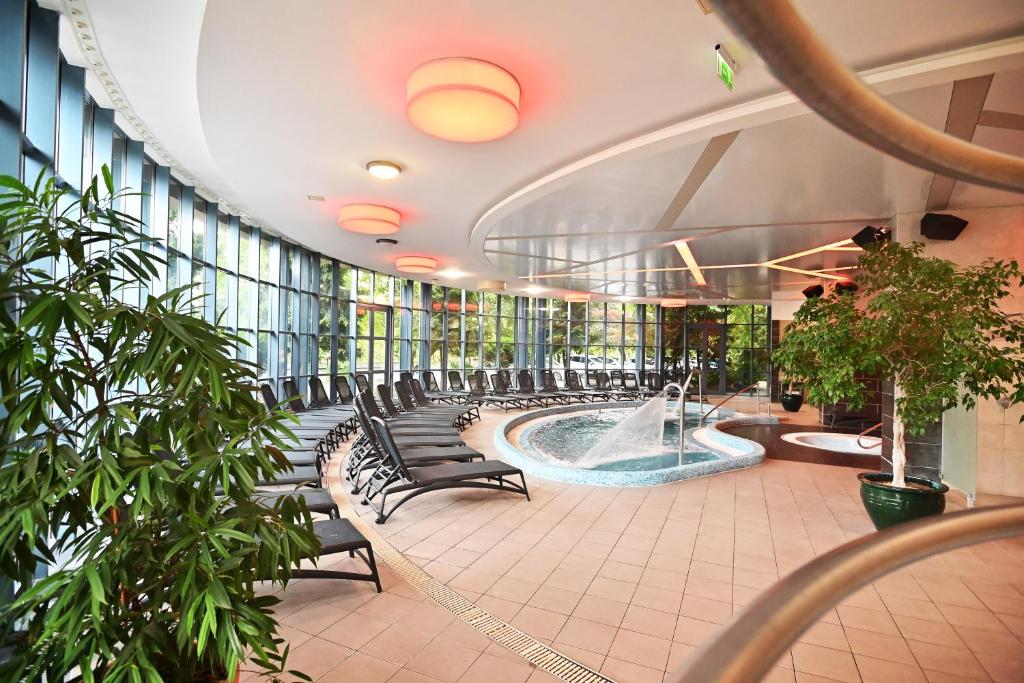 un grand bâtiment avec un bain à remous et des chaises dans l'établissement Hotel Eger & Park, à Eger