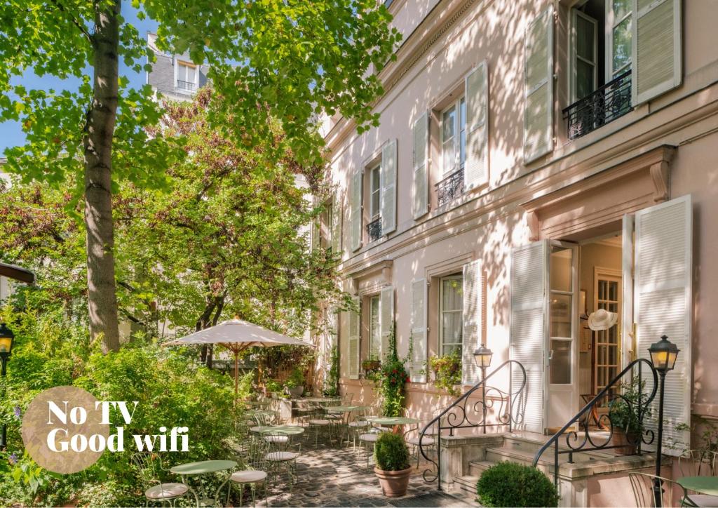 un patio con mesas y una sombrilla junto a un edificio en Hotel des Grandes Ecoles, en París