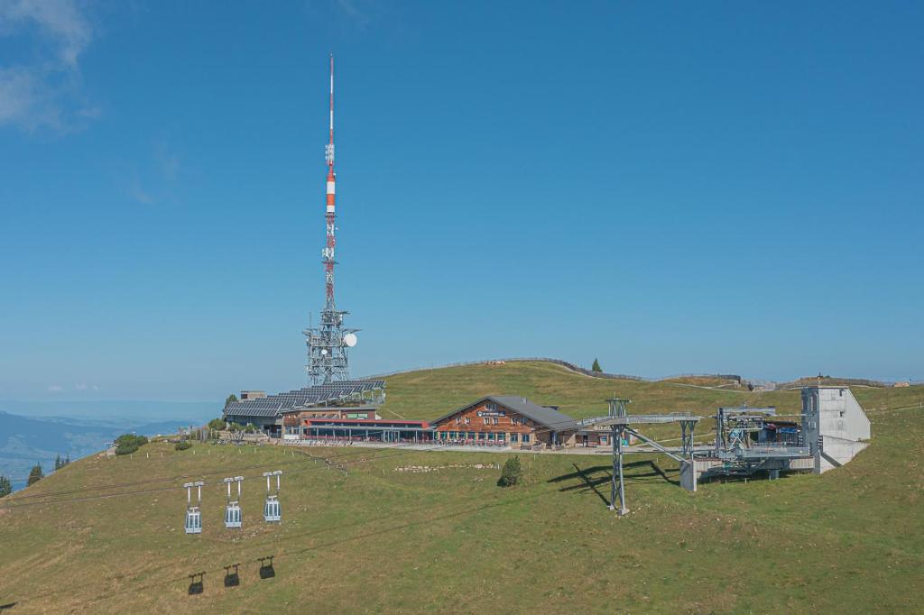 un bâtiment au sommet d'une colline avec une tour dans l'établissement Berghaus Niederhorn, à Beatenberg