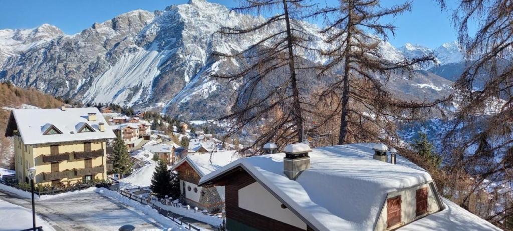 een met sneeuw bedekt dak met een berg op de achtergrond bij Stelviostay Residence Stelvio in Valdisotto