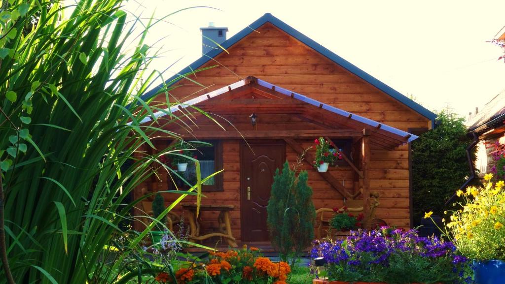 a log cabin with flowers in front of it at Cztery Pory Roku - Domek 