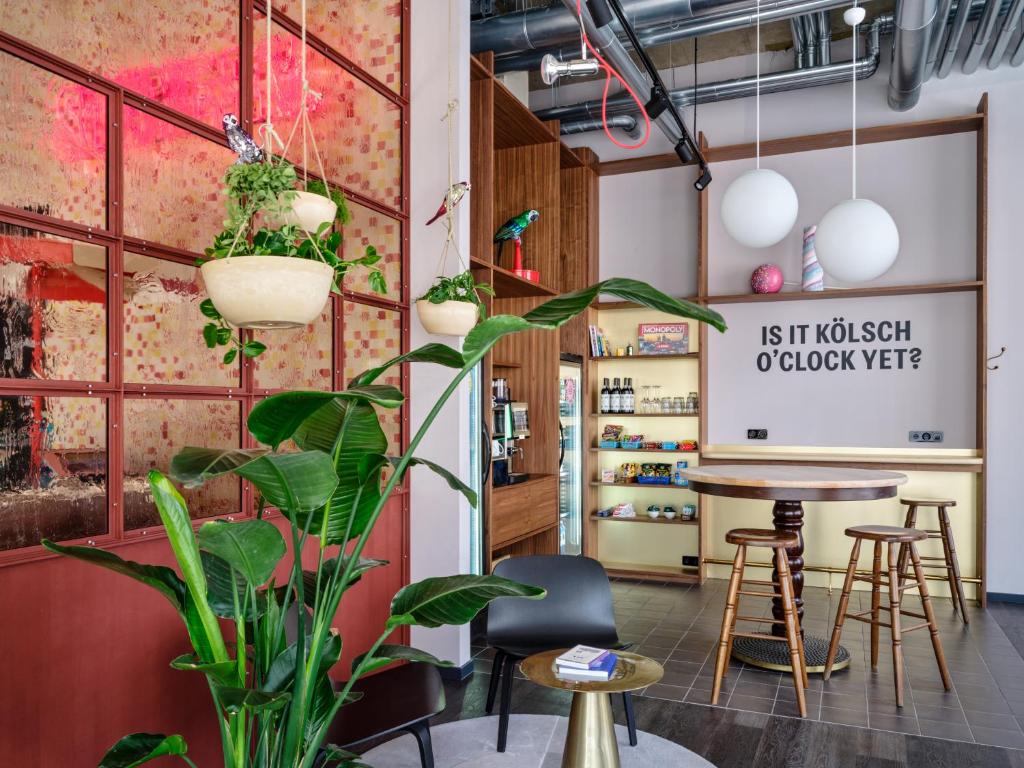 a room with a table and chairs and plants at STAYERY Cologne Ehrenfeld in Cologne