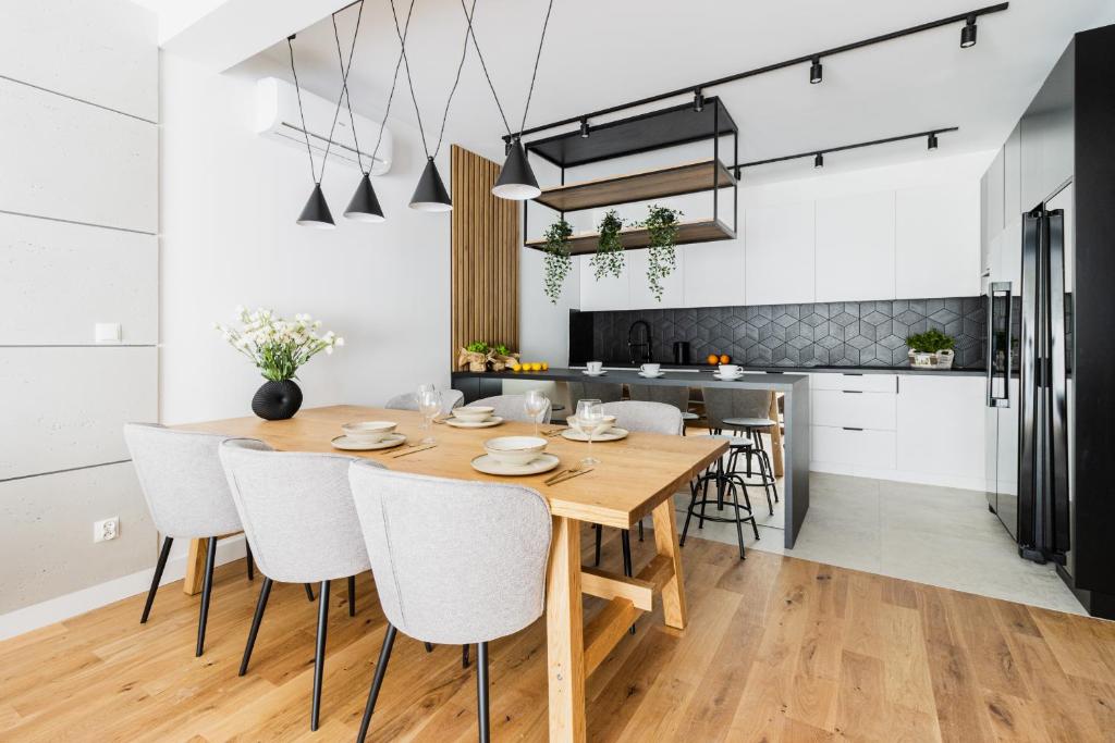 uma cozinha e sala de jantar com uma mesa de madeira e cadeiras em KOBIELA Luxury Aparthotel KTW City Center em Katowice