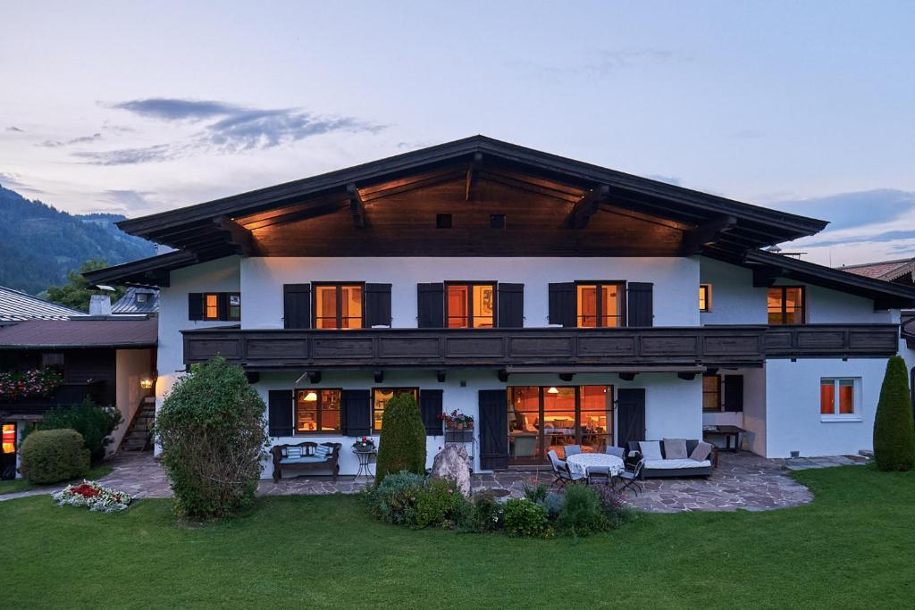 une grande maison blanche avec un toit en gambrel dans l'établissement Pension Landhaus Gasteiger, à Kitzbühel