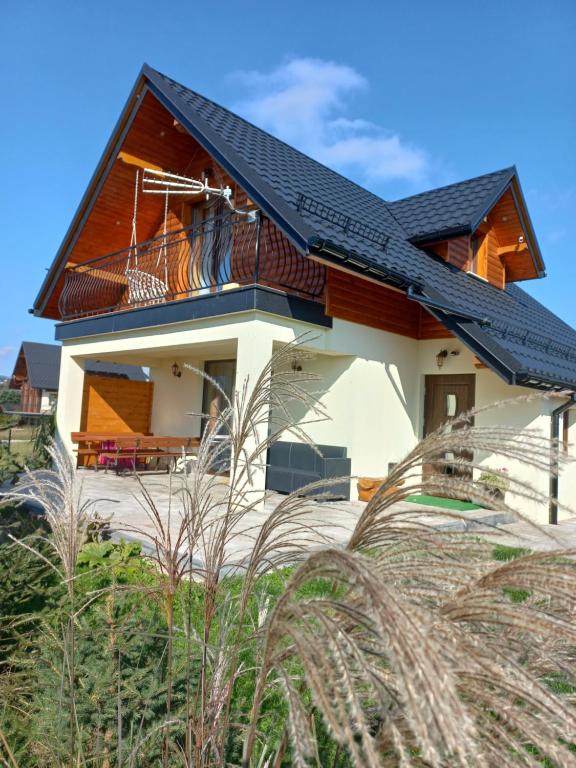 une maison avec un toit noir dans l'établissement Domek na Hubce II, à Maniowy