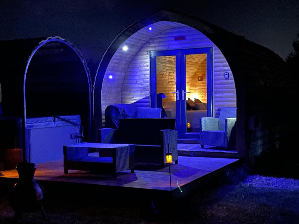 ein dunkles Zimmer mit einem Sofa und Stühlen in einem Zelt in der Unterkunft Little Meadow Pods with Hot Tub in York