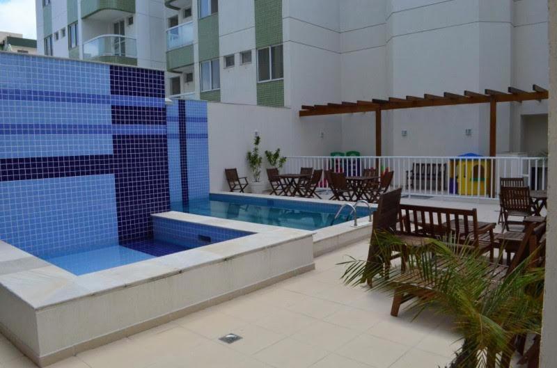 una piscina con mesas y sillas junto a un edificio en Apto em Cabo Frio com conforto e qualidade., en Cabo Frío