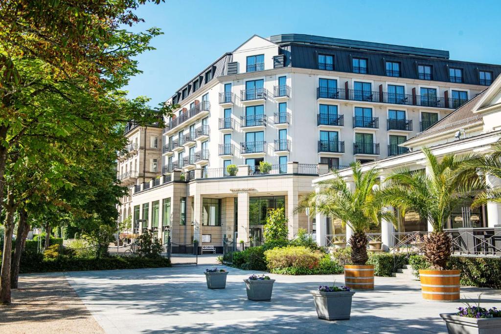 een groot wit gebouw met bomen ervoor bij Maison Messmer - ein Mitglied der Hommage Luxury Hotels Collection in Baden-Baden