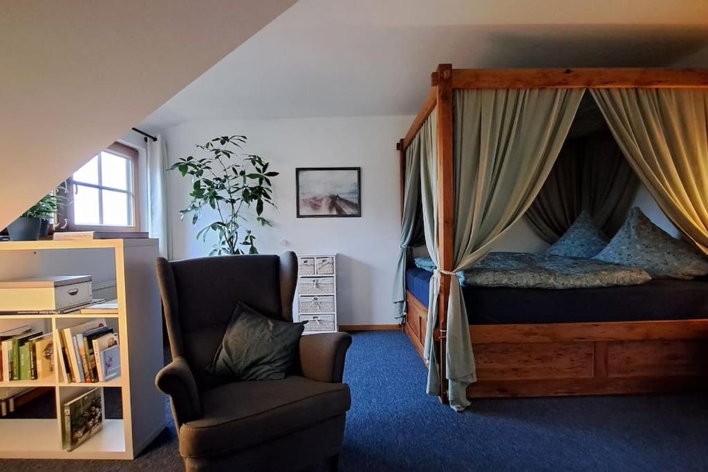 um quarto com uma cama de dossel e uma cadeira em Gemütliche Waldrandlage in Badenweiler Sehringen Ferienwohnung em Badenweiler