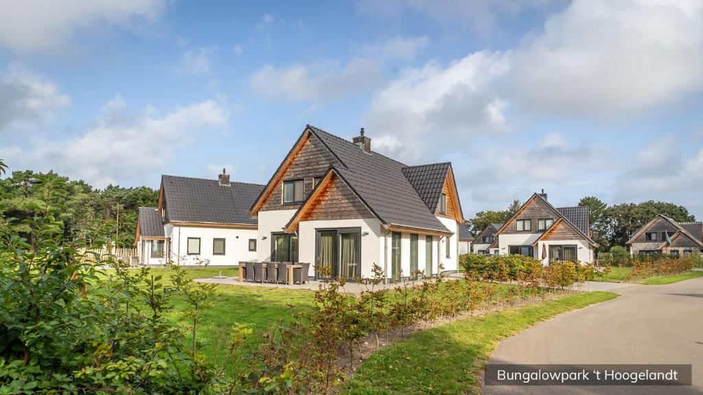 ein weißes Haus mit schwarzem Dach in der Unterkunft Bungalowpark 't Hoogelandt in De Koog