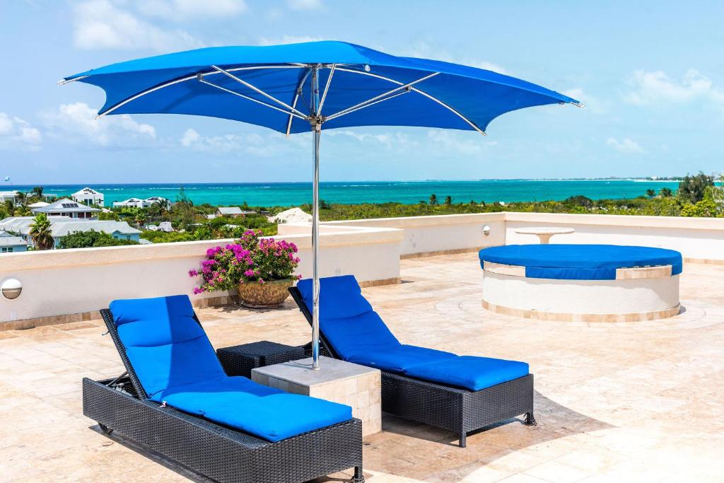 un par de sillas azules y una sombrilla en un patio en Sea Esta Studio I - Ideal for Couples!, en Turtle Cove