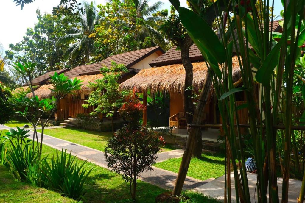 a house with a thatched roof in a garden at Waroeng Senaru in Senaru