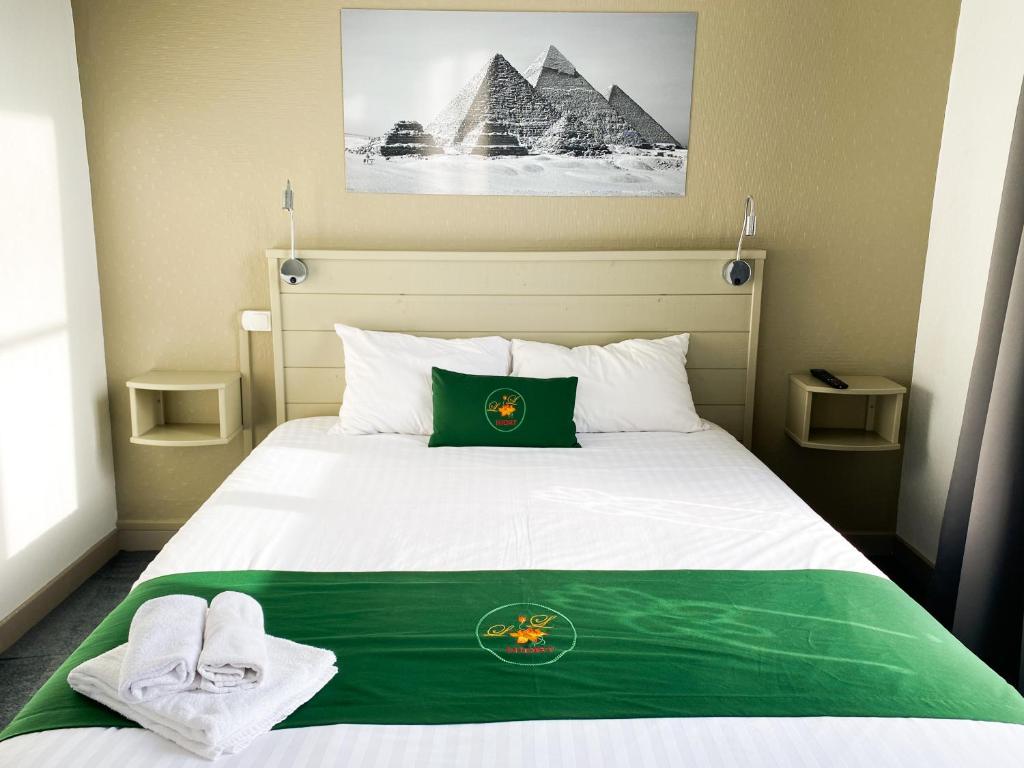 - une chambre dotée d'un lit avec une couverture verte et des pyramides dans l'établissement Colette Hôtel, à Niort