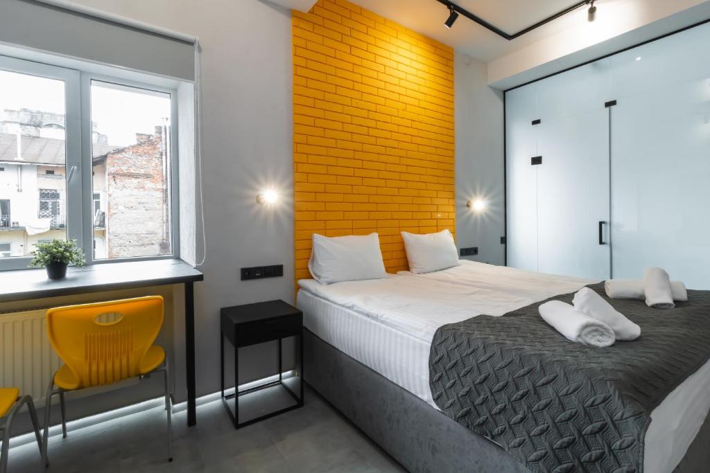 1 dormitorio con cama y pared de ladrillo amarillo en Stories Hub, en Leópolis