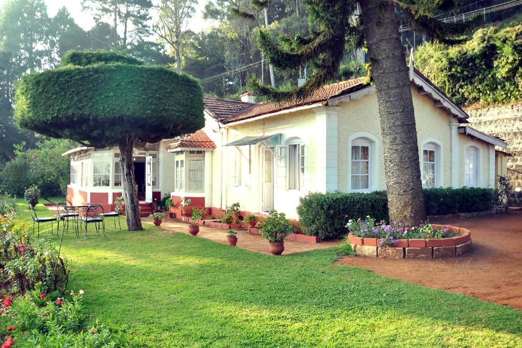 een huis met een boom en bloemen in een tuin bij Wyoming Heritage in Ooty