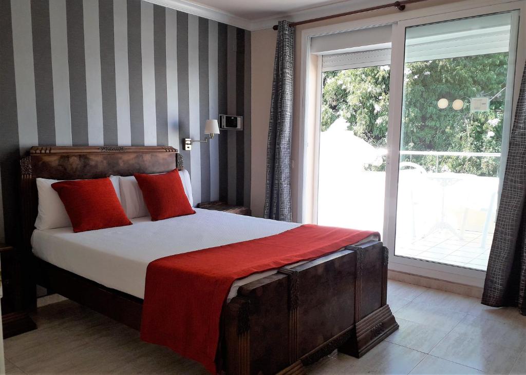 - une chambre avec un lit doté d'oreillers rouges et une fenêtre dans l'établissement Hotel Noucentista, à Sitges