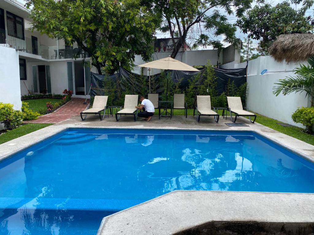 uma piscina azul com cadeiras e um guarda-sol em Hotel fresno Xochitepec em Chiconcuac