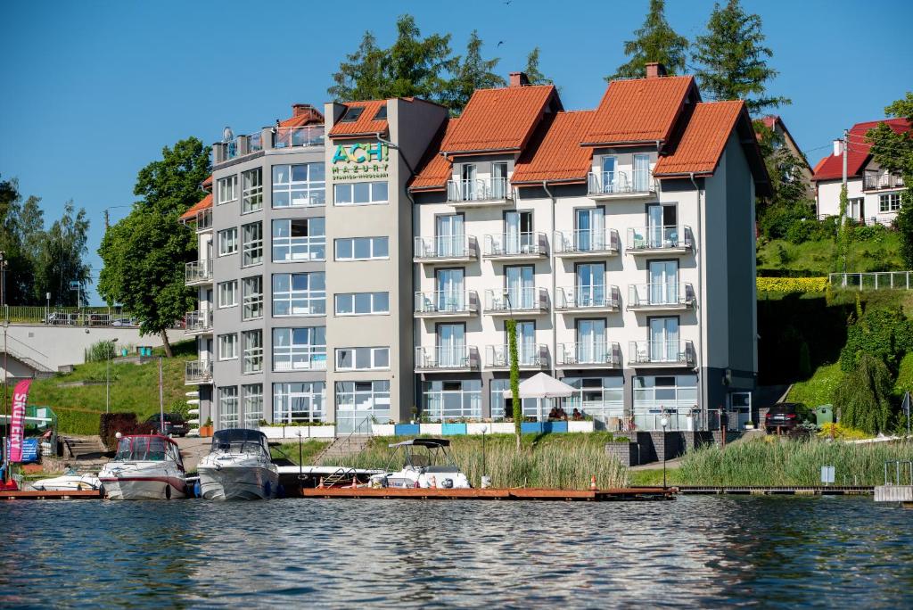 un edificio en el agua con barcos delante en Ach Mazury, en Mikołajki