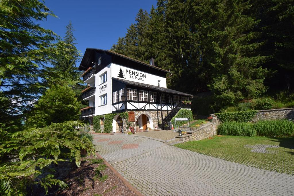 um edifício branco e preto com árvores ao fundo em Pension St. Moritz em Železná Ruda