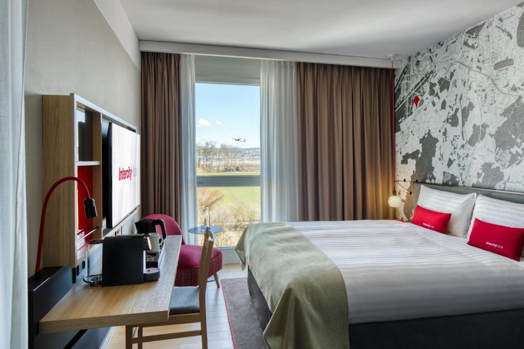 Habitación de hotel con cama, escritorio y ventana en IntercityHotel Zürich Airport, en Rümlang