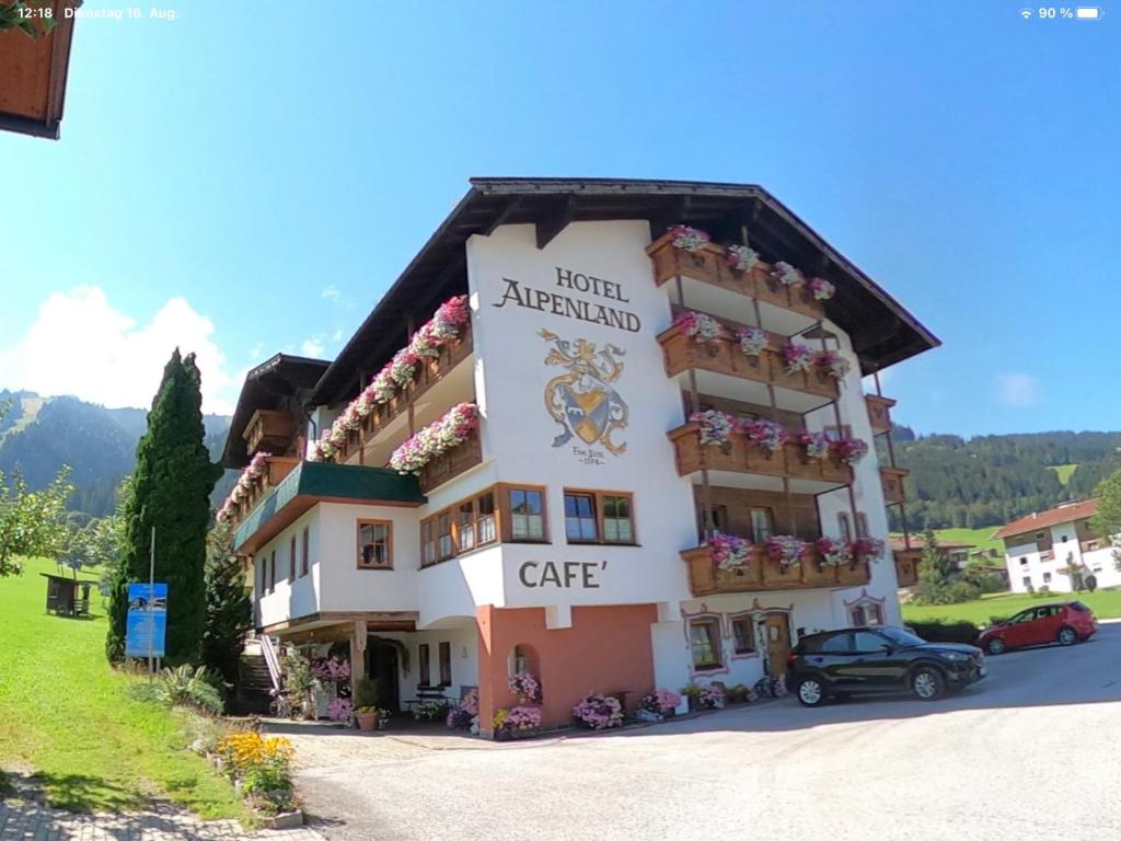 un hotel en las montañas con un coche aparcado delante en Hotel Alpenland, en Niederau