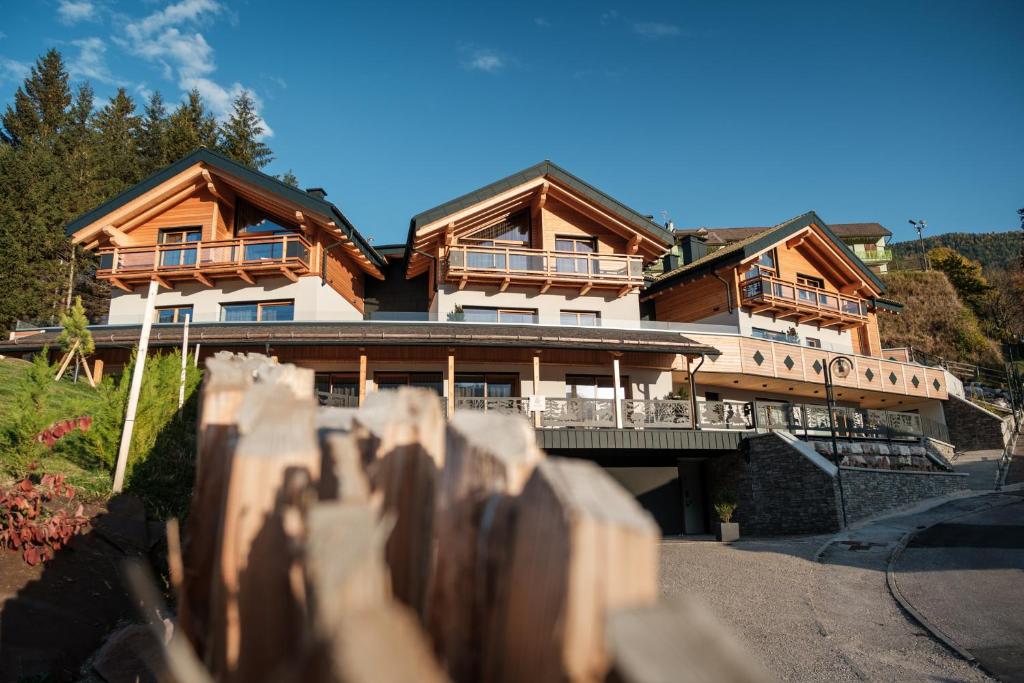 ein großes Holzhaus mit einem Zaun davor in der Unterkunft La Dila Dolomiti Mountain Lodge in Andalo