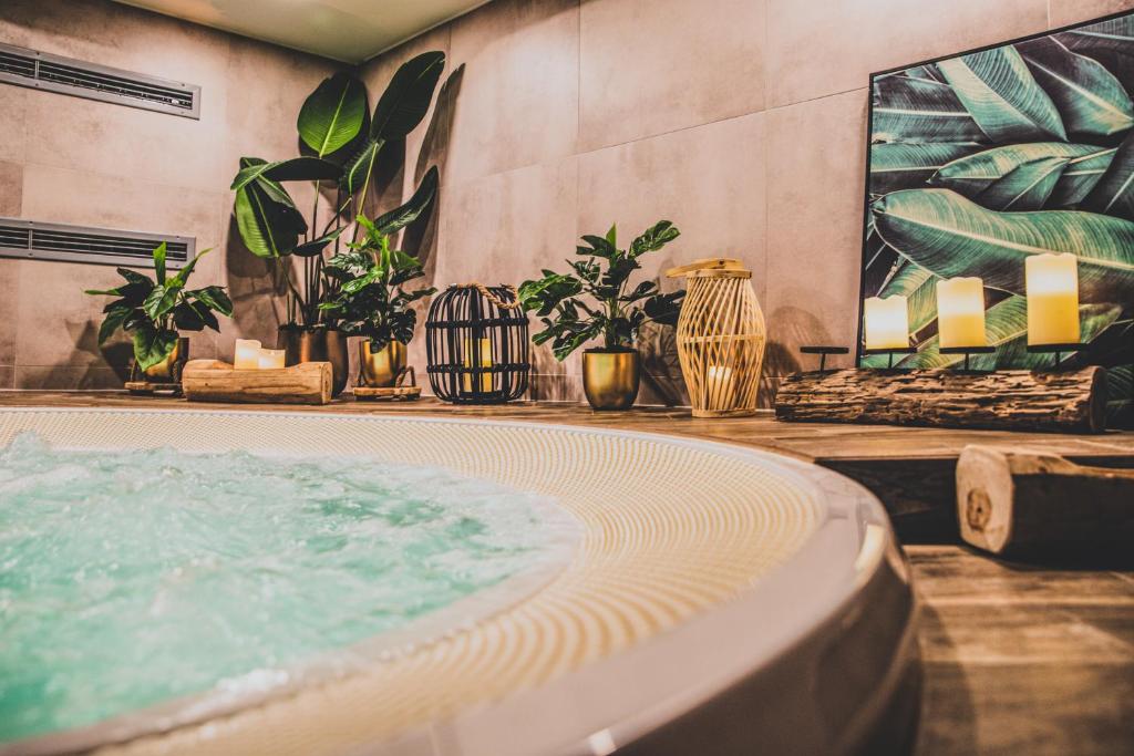 La salle de bains est pourvue d'un bain à remous avec des plantes et des bougies. dans l'établissement TatryTop Apartamenty Alpejski SPA, à Kościelisko