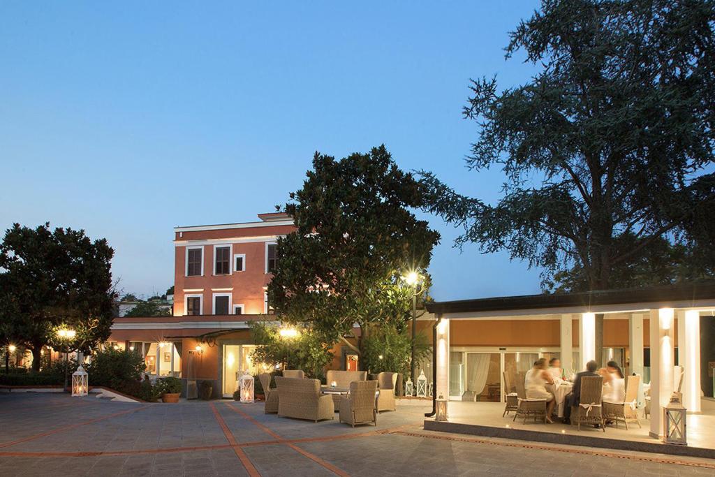 een groep mensen die buiten een gebouw in stoelen zitten bij Montespina Park Hotel in Napels