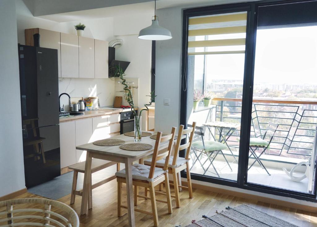 een keuken met een tafel en stoelen en een balkon bij Sunlight Apartment in Skopje