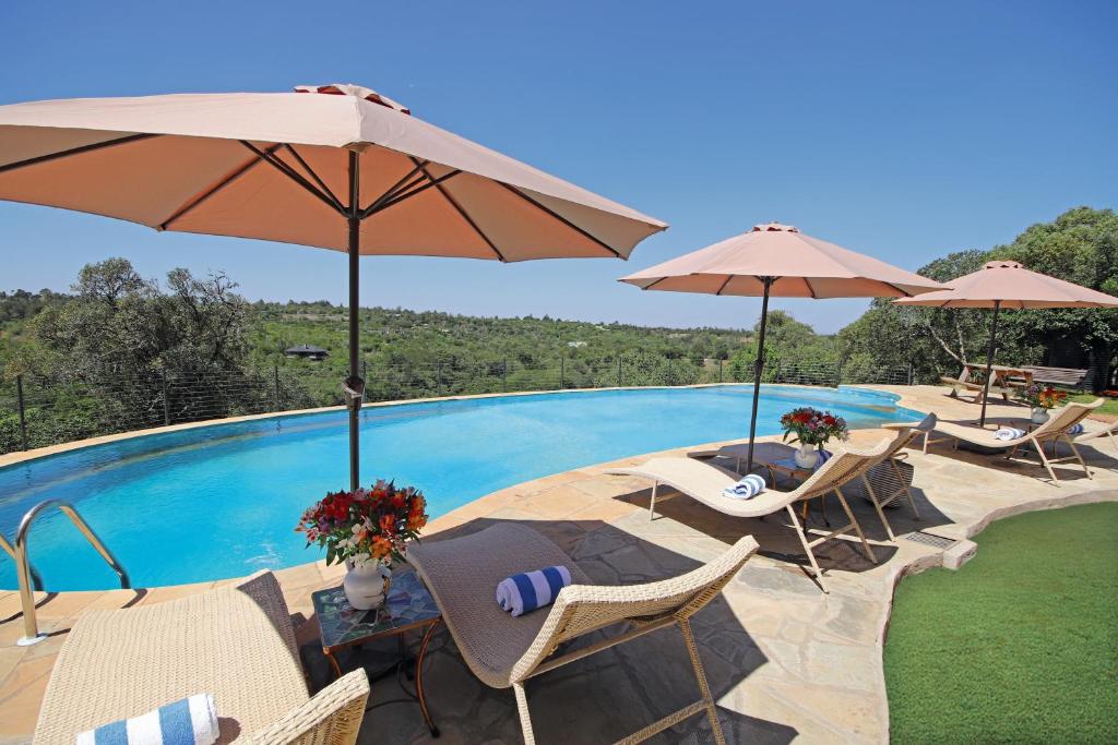 een zwembad met stoelen en parasols naast een zwembad bij Olesamara Collection in Nanyuki