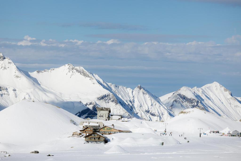 un edificio nella neve con montagne sullo sfondo di Berghotel Engstligenalp ad Adelboden