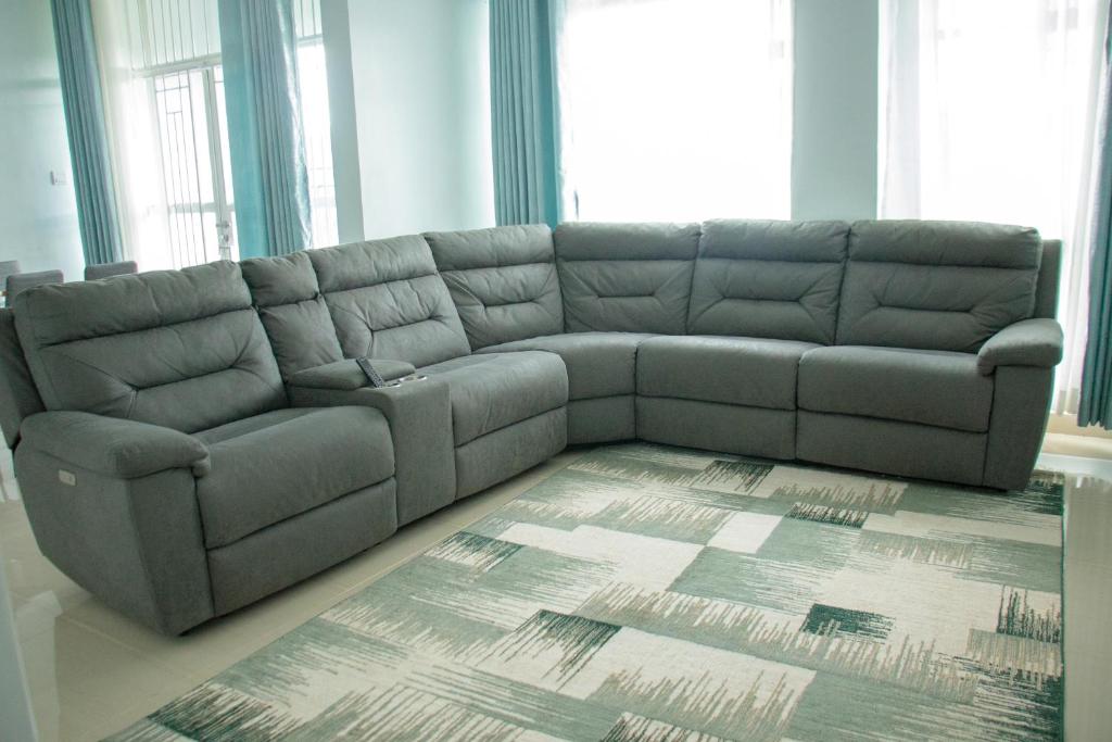 eine graue Couch in einem Wohnzimmer mit einem Teppich in der Unterkunft Zoe Homes 1br and 2br Apartment Greypoint 406 in Kericho