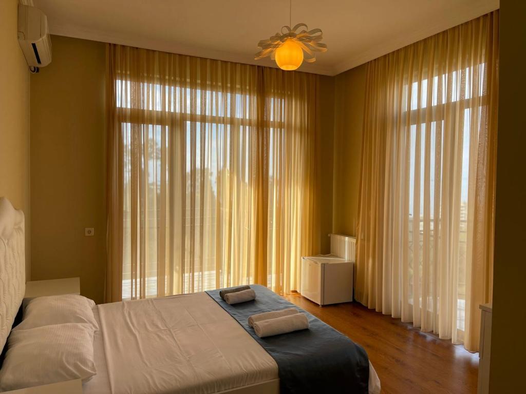 a bedroom with two beds and a large window at Green Yard Hotel in Batumi