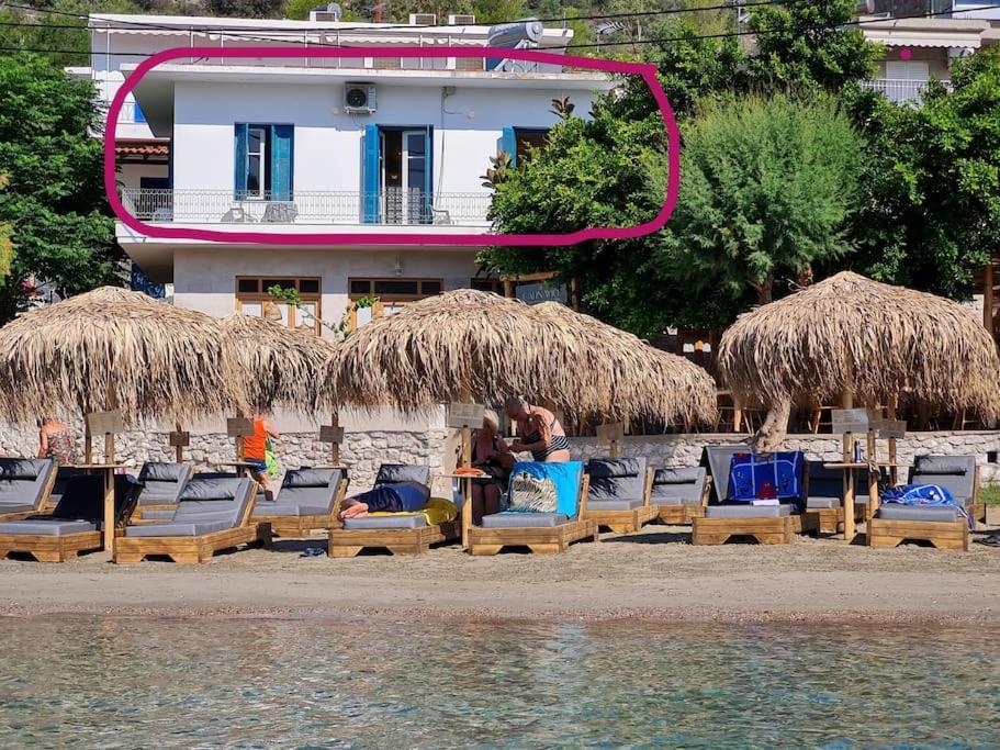 a group of chairs and straw umbrellas on a beach at Big apartment on the beach in Tolo