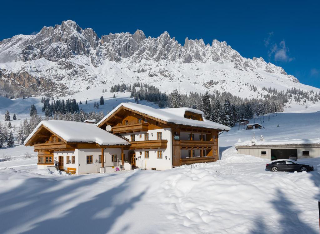 uma casa na neve com uma montanha ao fundo em Gästehaus Gschwandtner em Mühlbach am Hochkönig