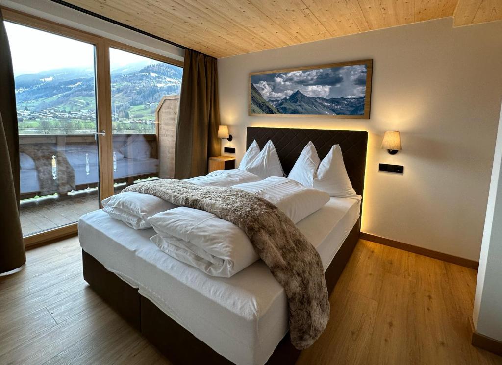 - une chambre avec un grand lit et une grande fenêtre dans l'établissement Pension Dorferwirt, à Bramberg am Wildkogel