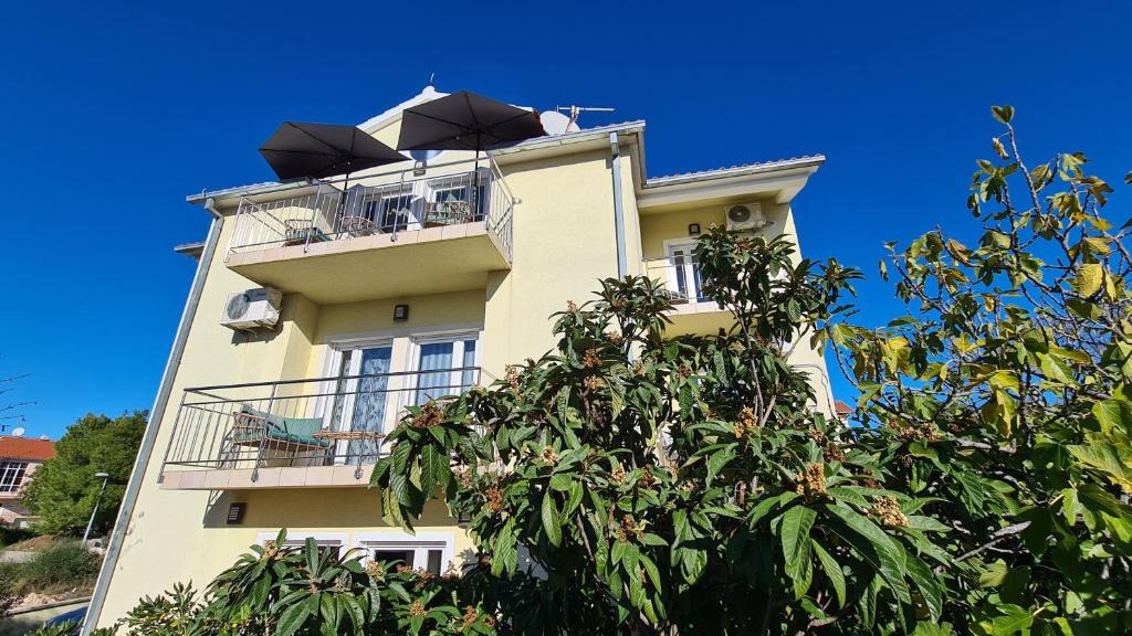 ein gelbes Gebäude mit Balkon und Sonnenschirm in der Unterkunft Villa Neda in Vodice