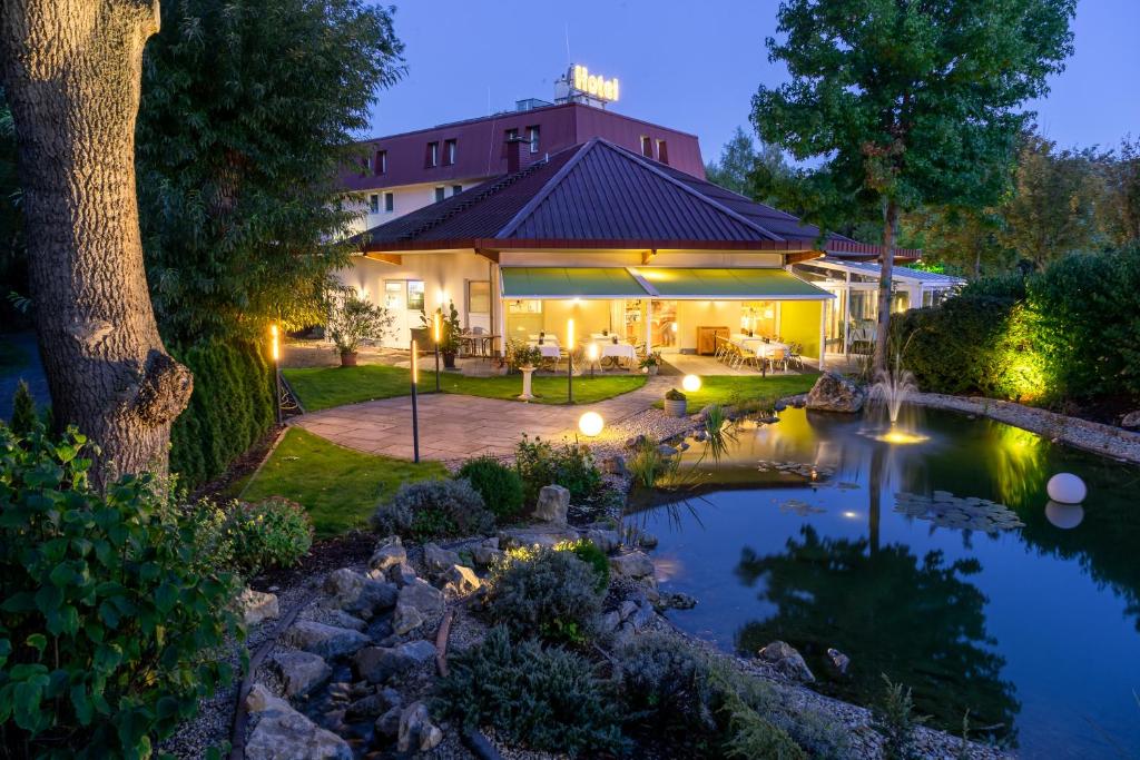 une maison avec un étang en face d'une maison dans l'établissement Hotel am Tierpark Gotha, à Gotha