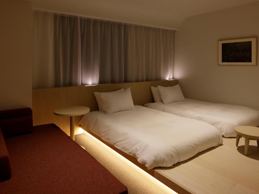 a hotel room with two beds and a table at SOKI Kanazawa in Kanazawa