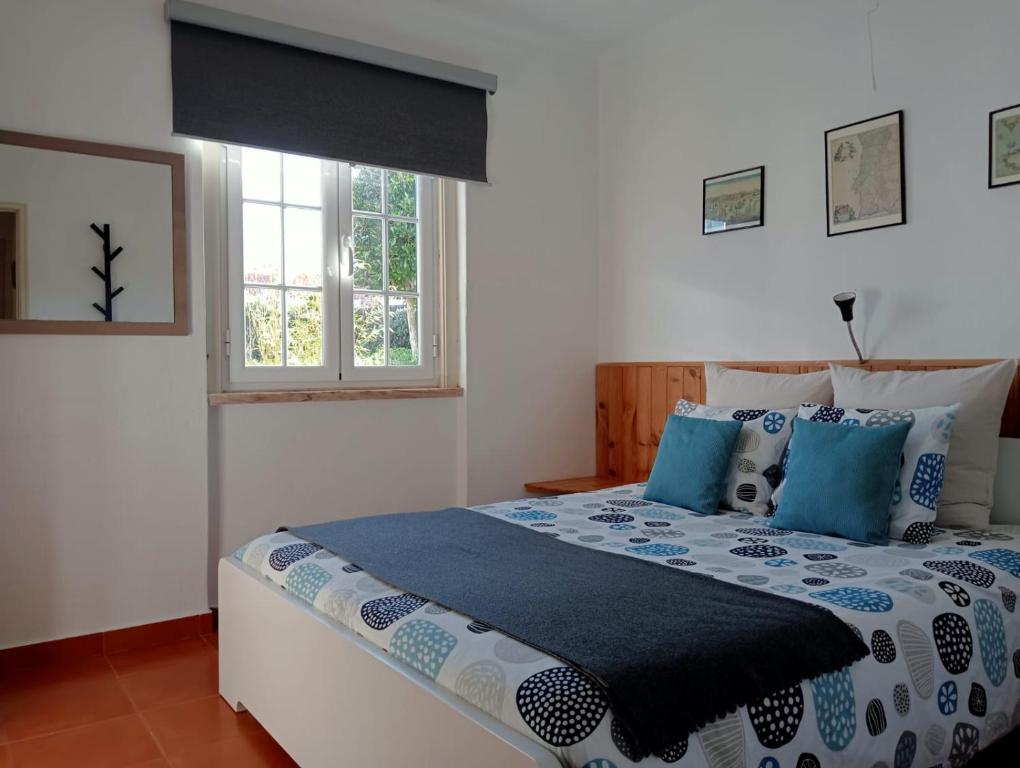 1 dormitorio con 1 cama grande con almohadas azules en casal do melro, en Ericeira