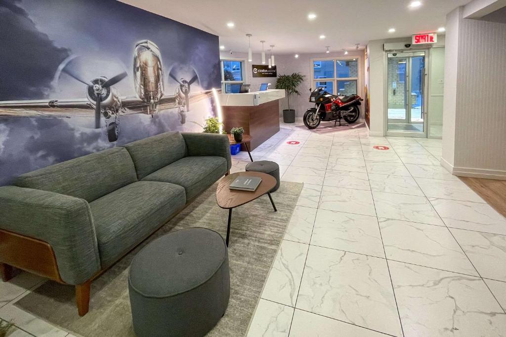 - un salon avec un canapé vert et une moto dans l'établissement Clarion Pointe Quebec Airport, à Québec