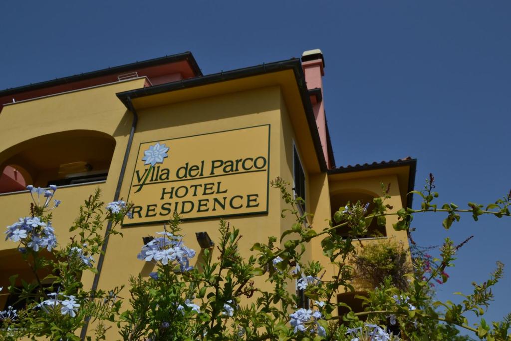 un cartello sul lato di un edificio con fiori di Hotel Villa Del Parco a La Maddalena