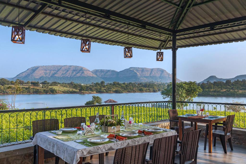 uma mesa com vista para um rio e montanhas em SaffronStays Lake House Bouganvillea, Nashik - rustic pool villa with great lake views and patio dining em Nashik