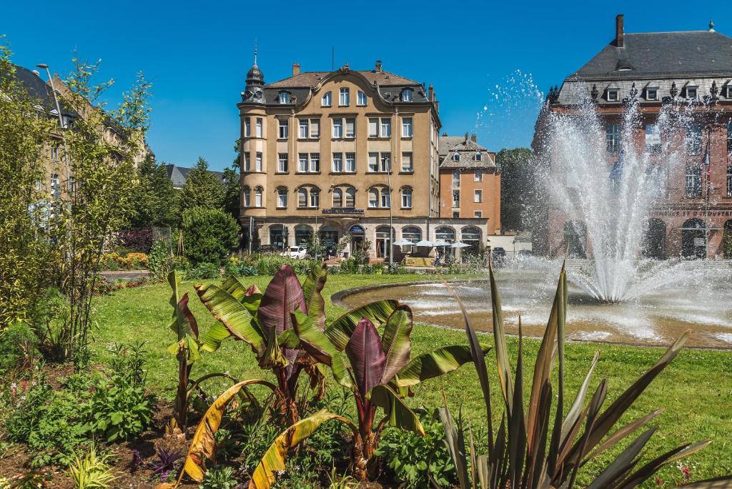 une fontaine en face d'un grand bâtiment dans l'établissement Hôtel Le Mondon Metz, à Metz