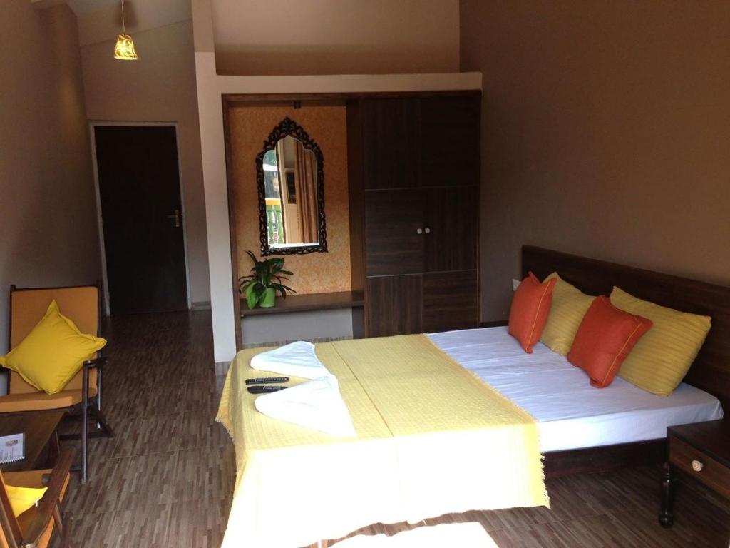 a bedroom with a large bed with orange and yellow pillows at Hotel Bonanza in Baga