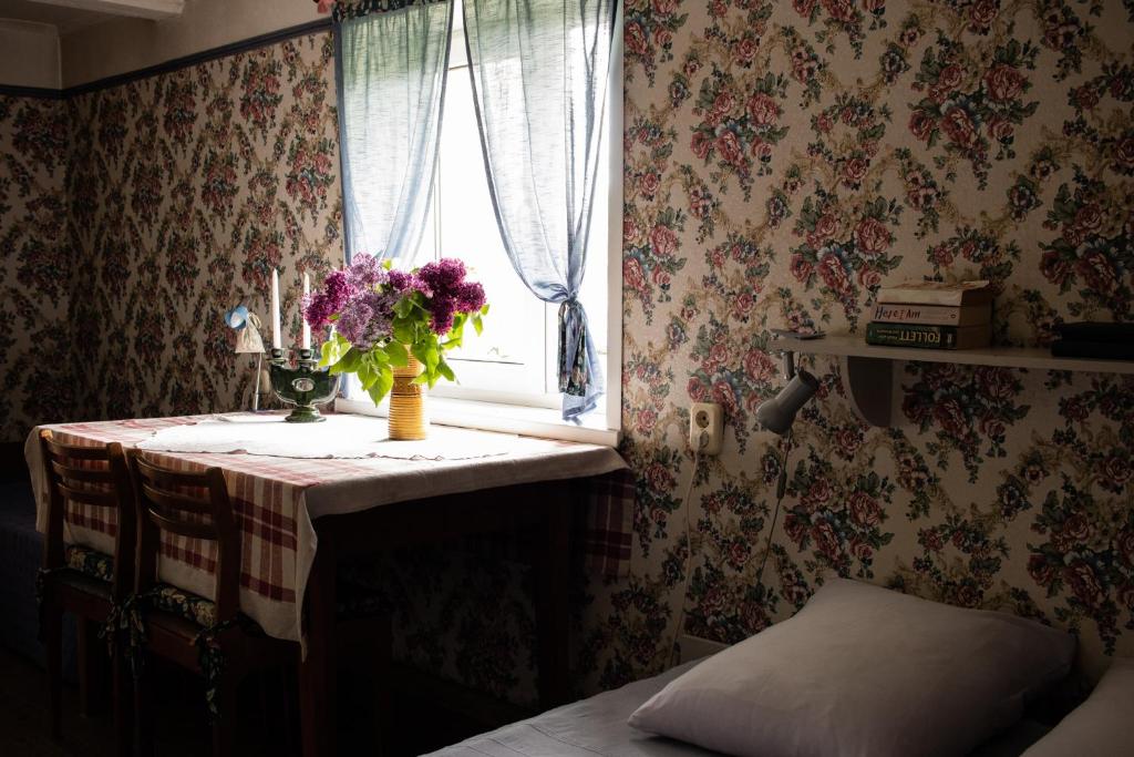 una mesa con un jarrón de flores y una ventana en Coastal Home Muini Ūši, en Kolka