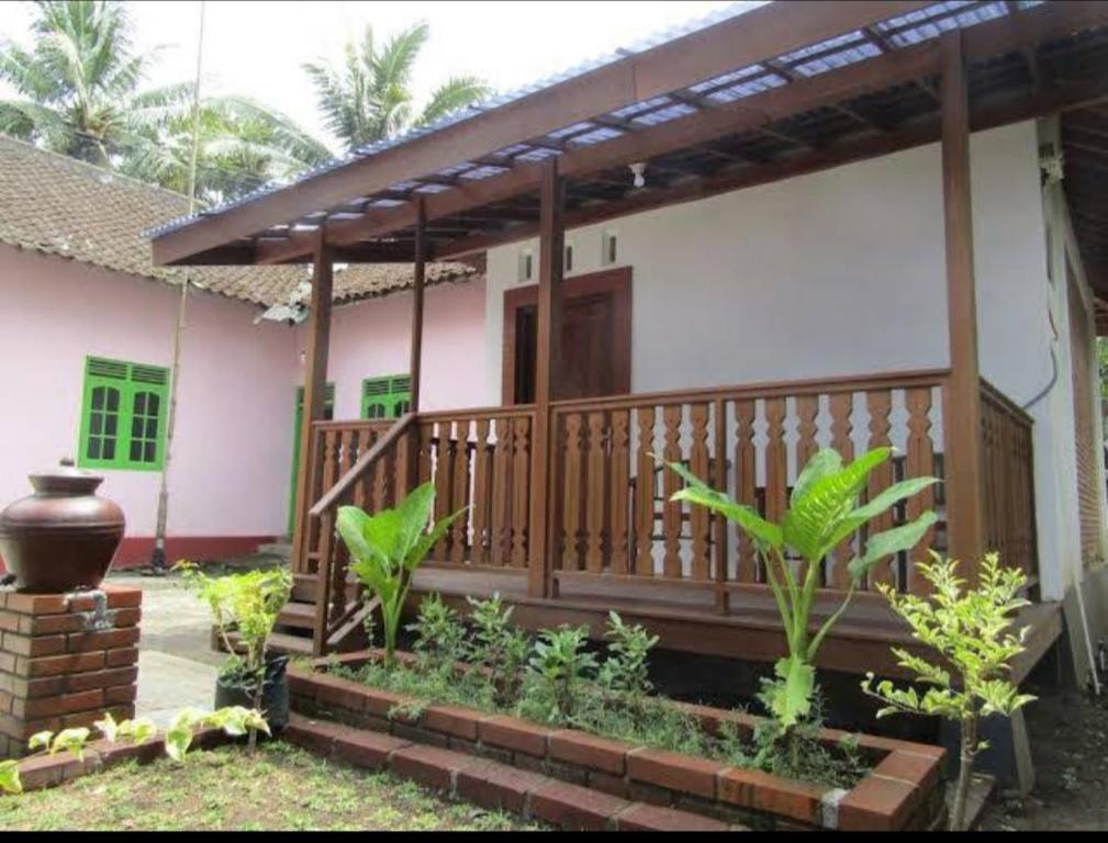 una casa con terraza de madera en un patio en Griya Sukatno, en Magelang